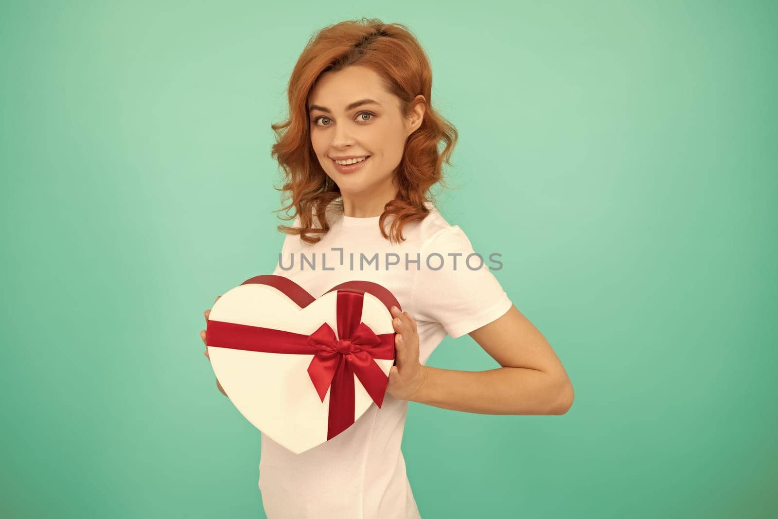 happy girl hold heart gift box on blue background.