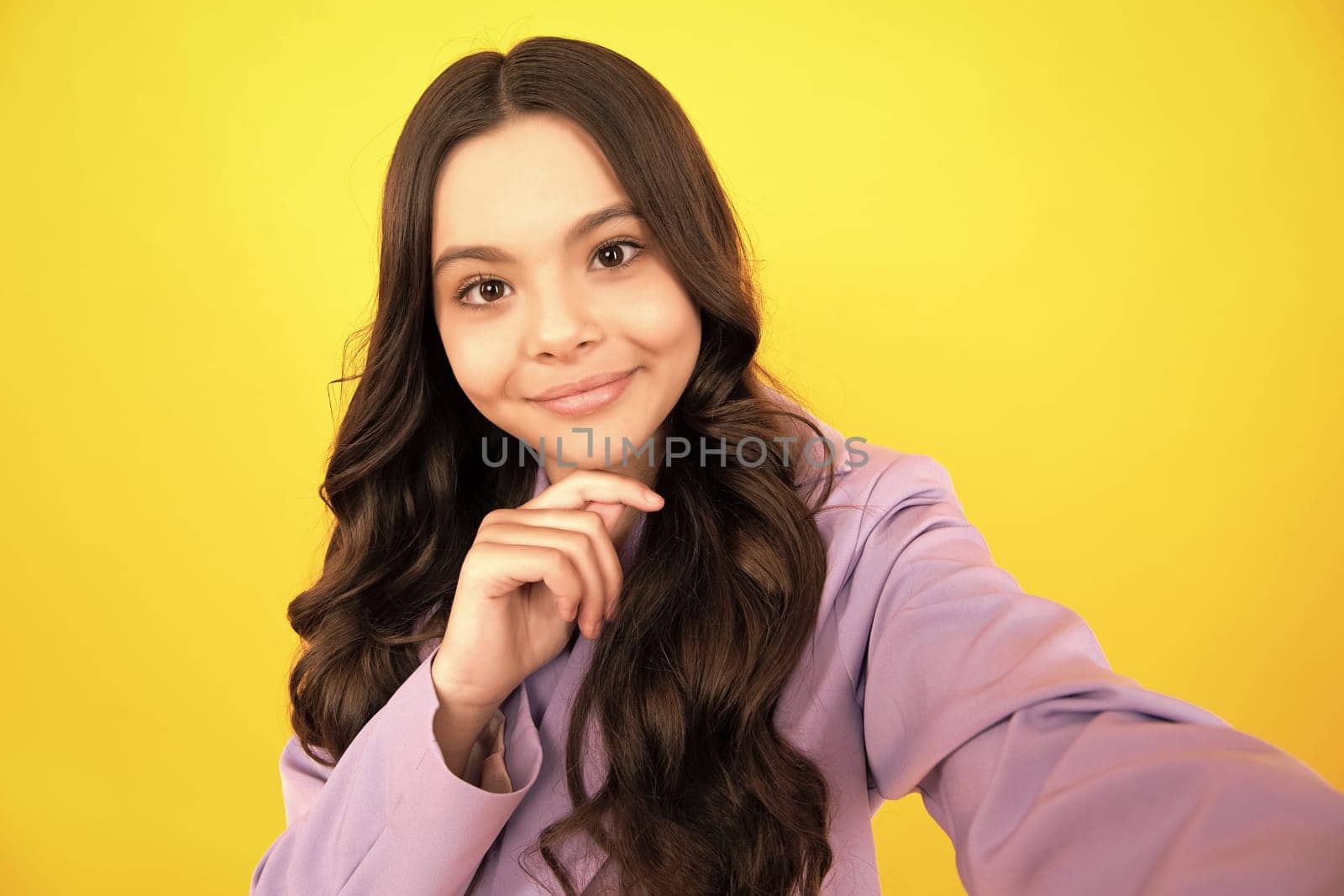Teenager lifestyle. Beautiful ateenager child girl in moder suit making selfie posingisolated on yellow background. Happy teenager, positive and smiling emotions of teen girl