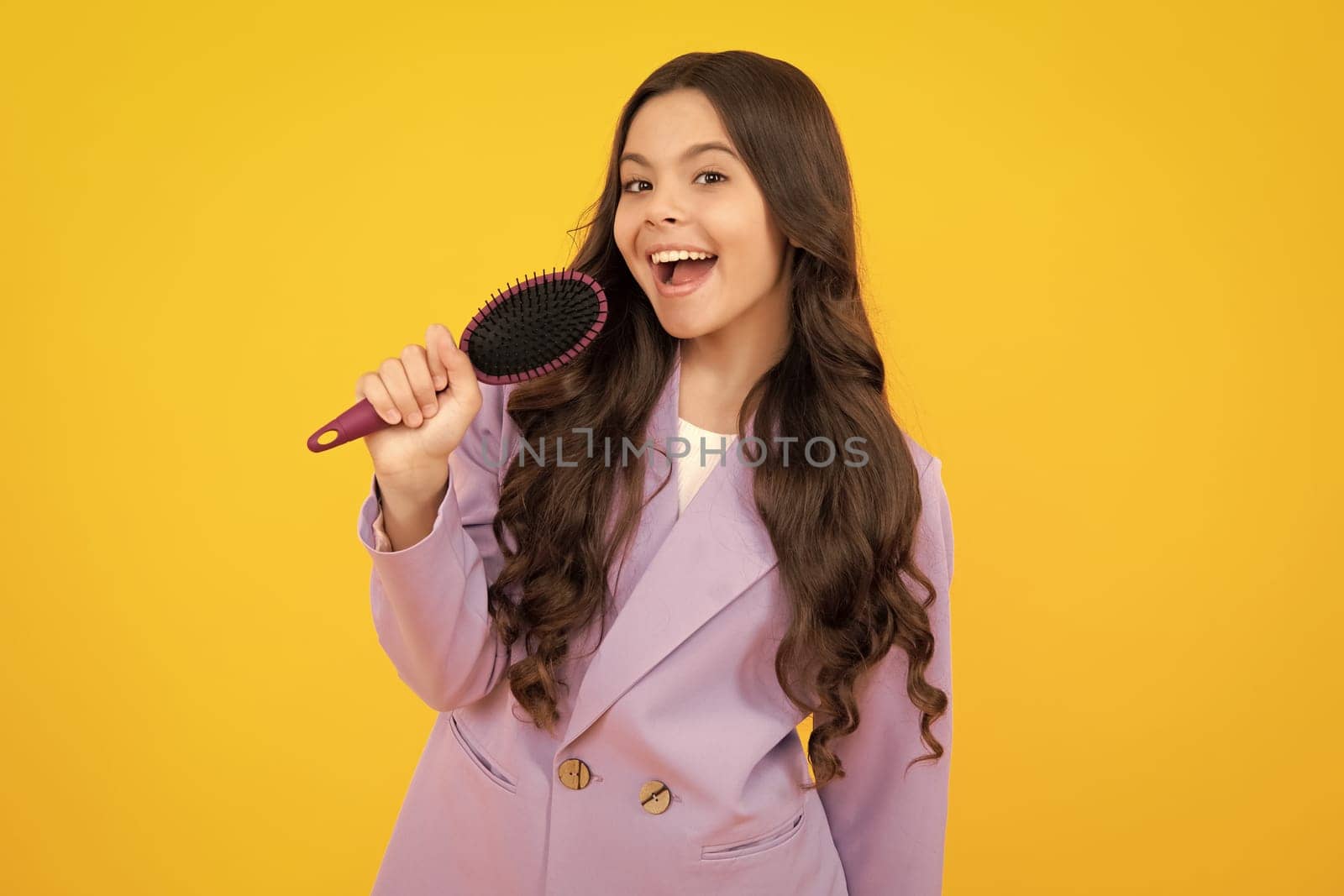 Child with long hair holding comb hairbrush for combing, beauty. Conditioner shampoo hair. Beauty kids salon. Child hairstyle. Happy face, positive and smiling emotions of teenager girl
