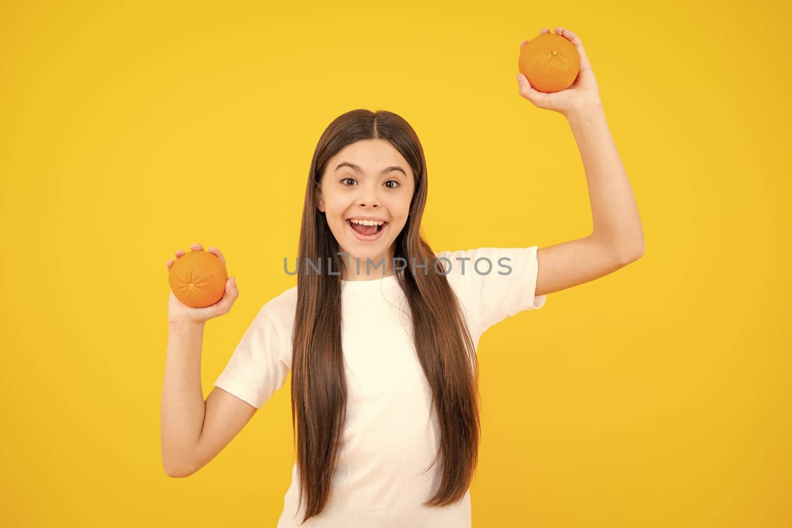 Excited teenager portrait. Teenage girl holding a grapefruit on a yellow background. Amazed girl