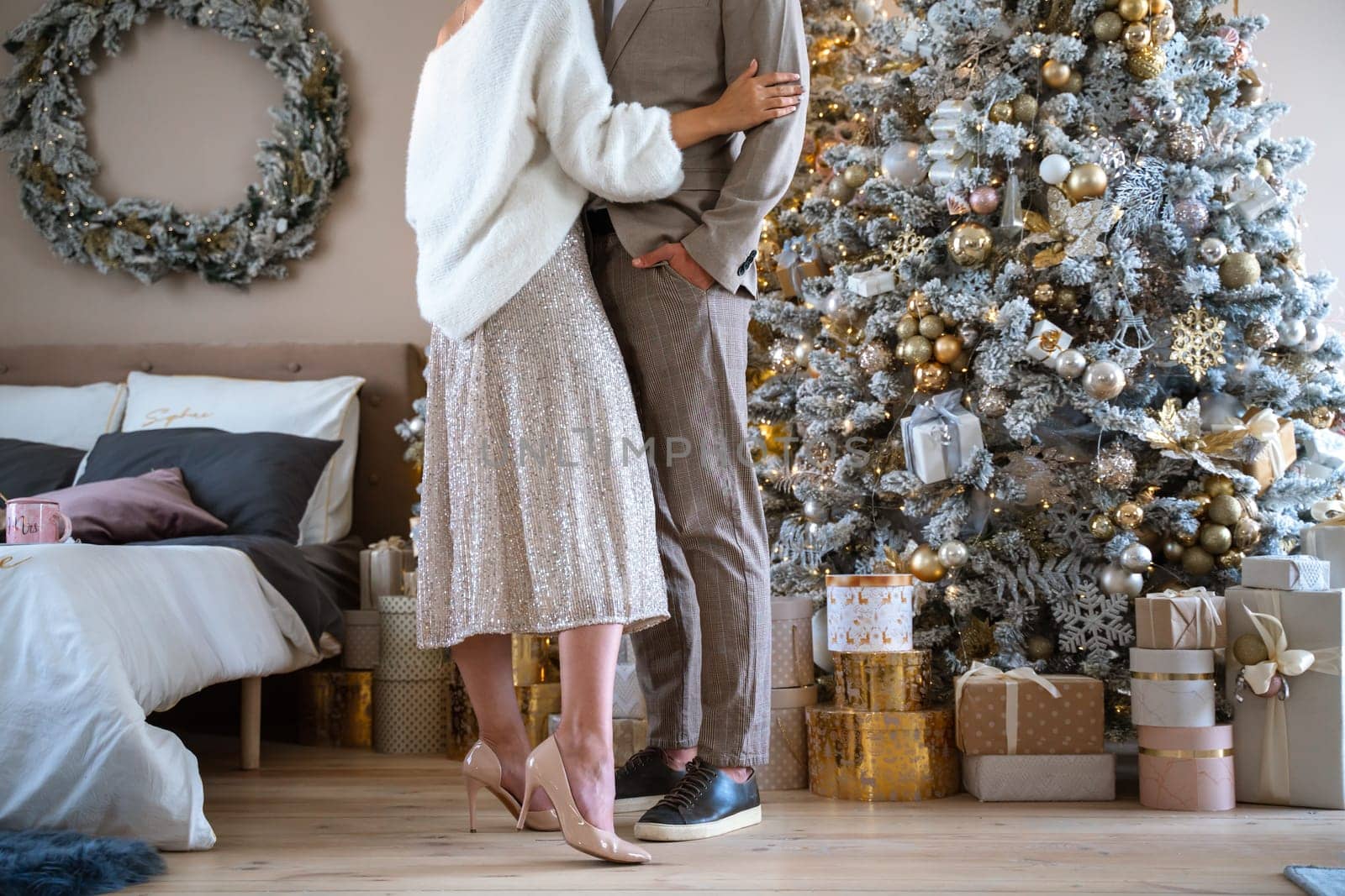 Romantic couple standing near Christmas tree at home and hugging.