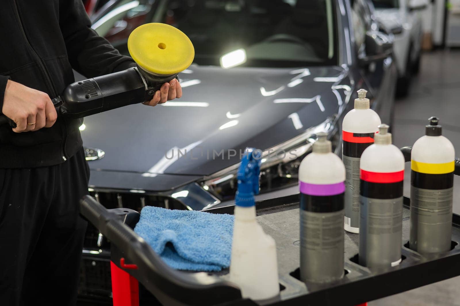 The master applies a special composition to the device for polishing the surface of the car body