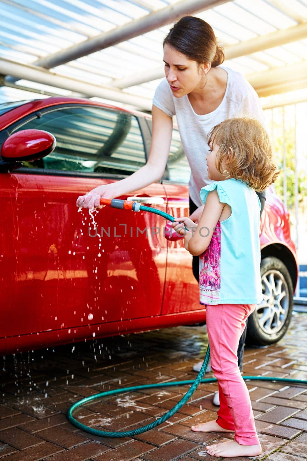 Mom, girl and washing car with teaching or learning for child development, growth and childhood memories. Parent, kid and enjoy with bonding, fun and educational with support and recreational at home.