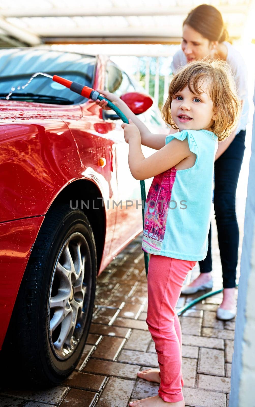 Portrait, kid and smile with washing car or learning for child development, growth and childhood memories. Mom, girl and enjoy with bonding, fun and educational for social teaching or support at home by YuriArcurs