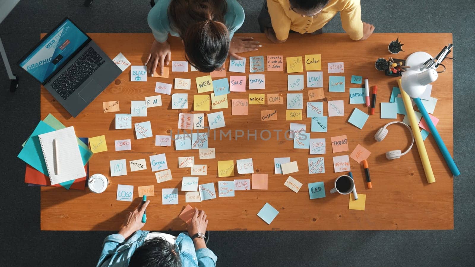 Top view of manager looking at idea on sticky notes and explain idea about web design. Skilled marketing team or programmer brainstorming idea while looking at tablet with color palette. Symposium.