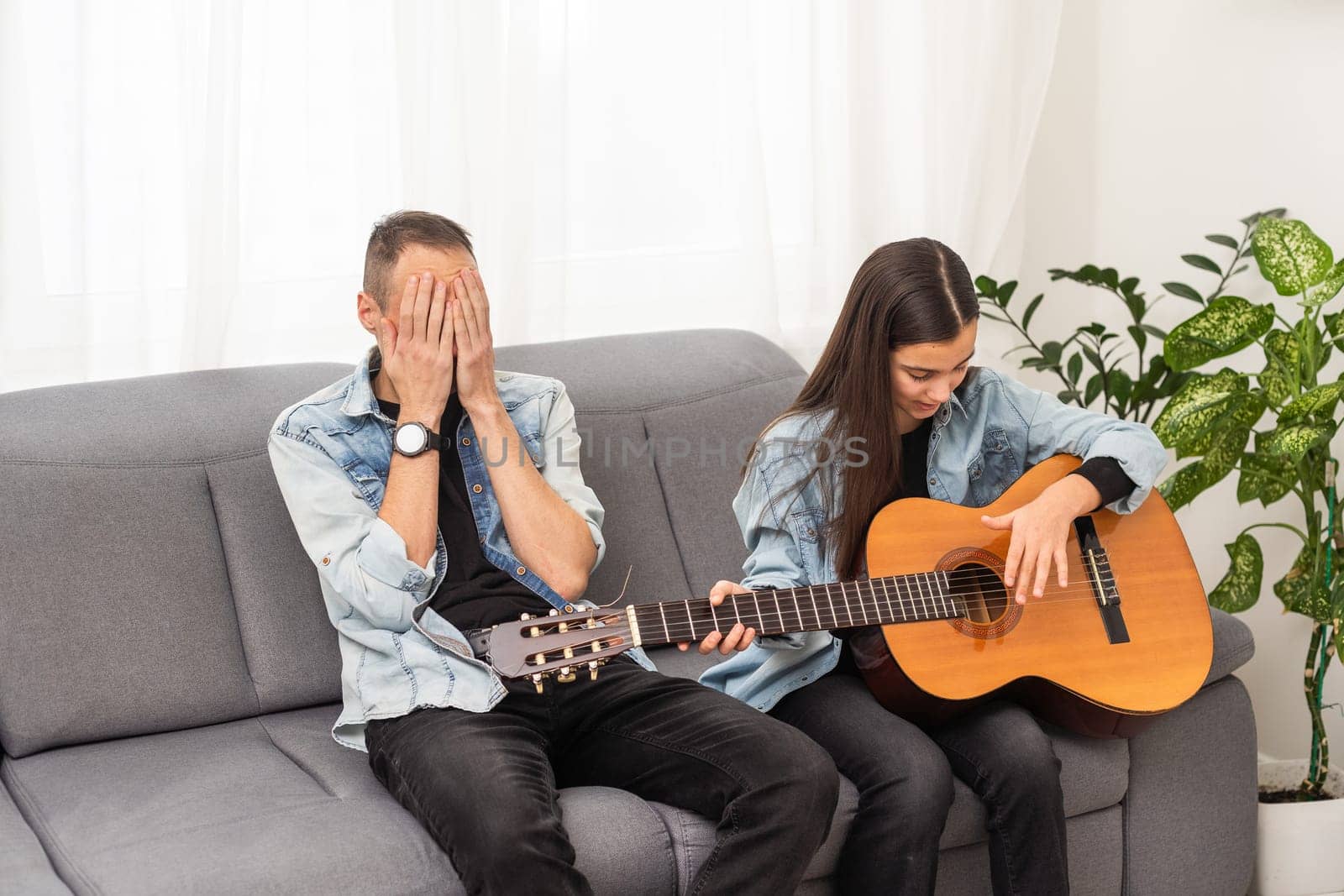 A father teaching his daughter how to play guitar. High quality photo