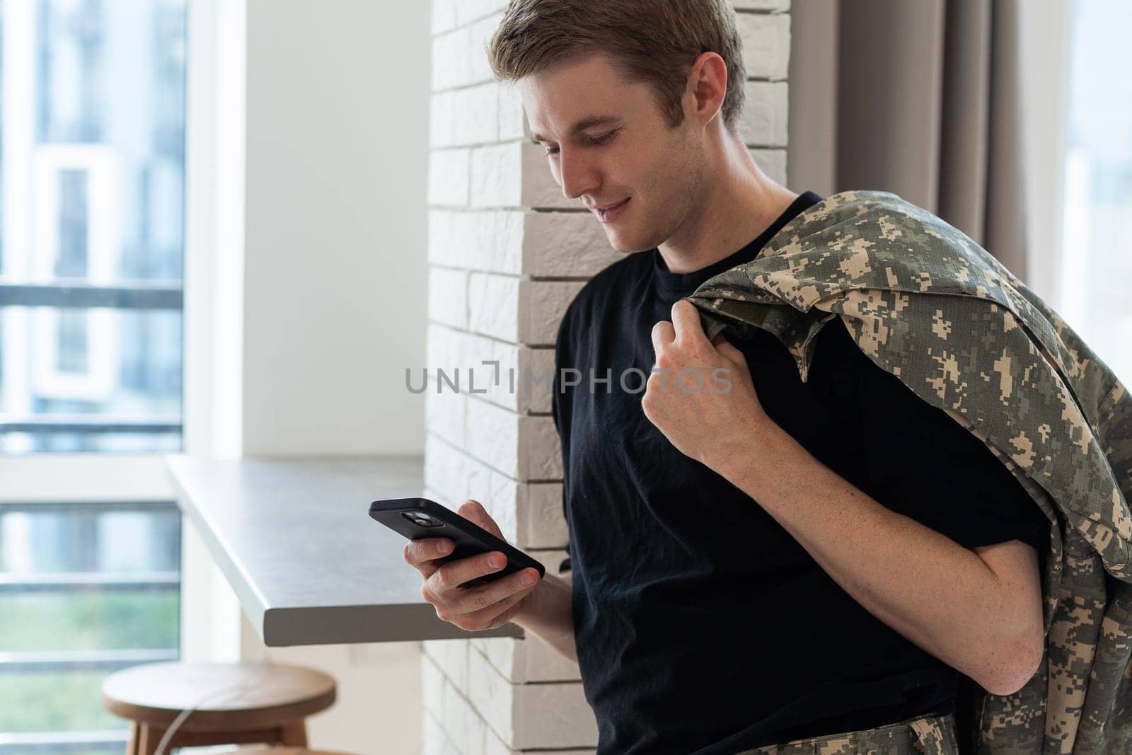 Young army man using smartphone at home.