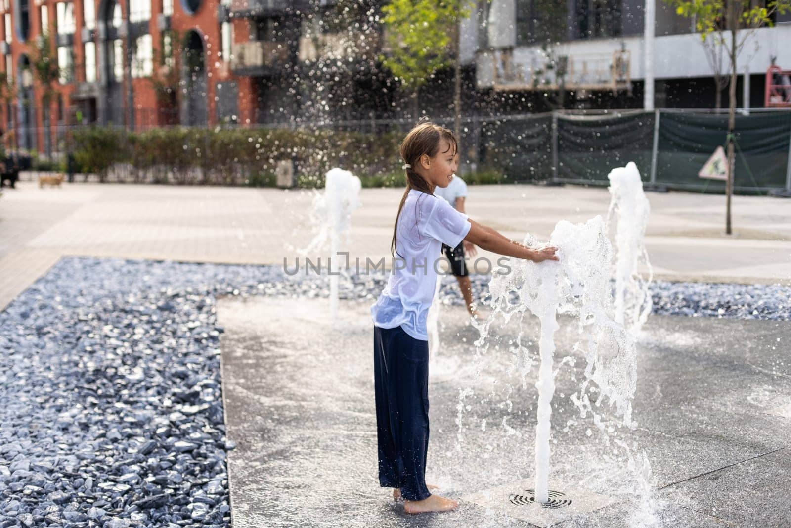 Happy kid playing in a fountain with water. High quality photo
