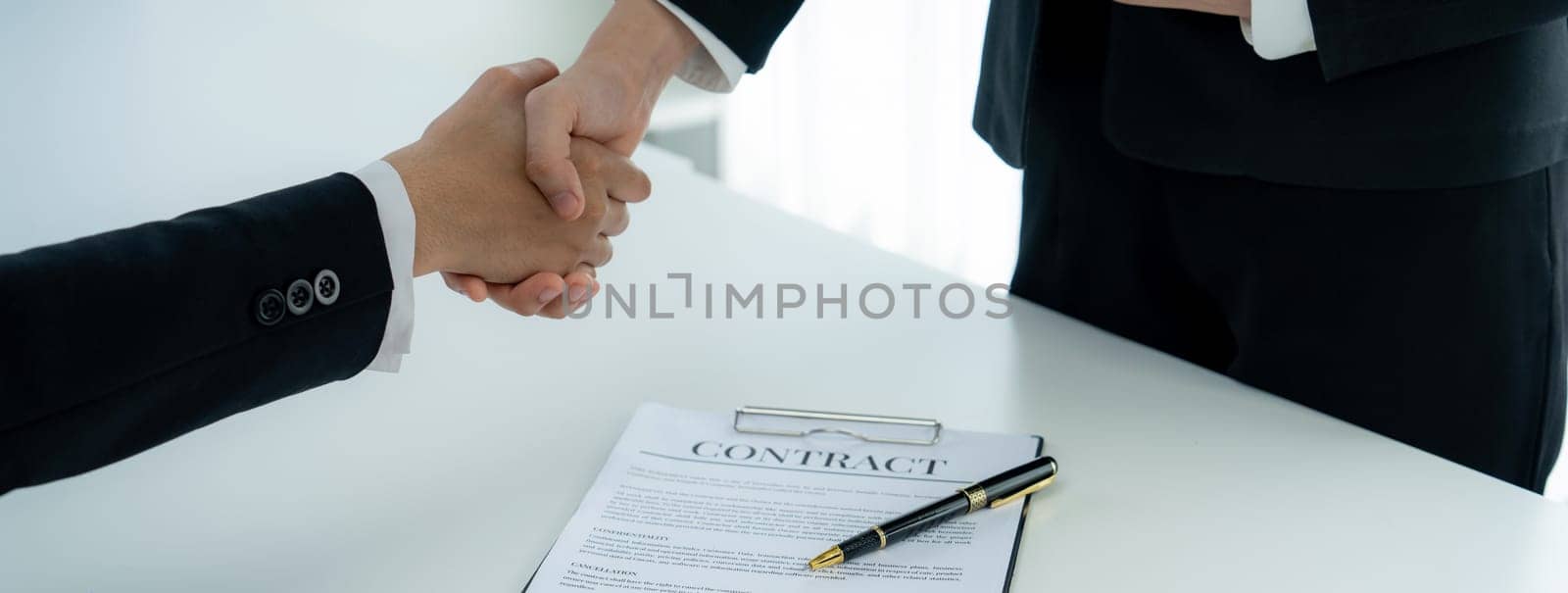 Two business executive shake hand in boardroom, sealing agreement merging two company. Handshake symbolize business partnership and cooperation. Corporate acquisition and merger concept. Shrewd