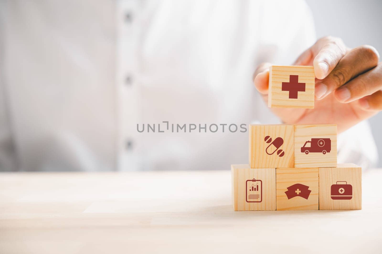 Captured moment, Hand grips wooden block with healthcare and medical icons. Portrays safety, health, and family well-being, symbolizing pharmacy, heart care, and happiness. health care concept