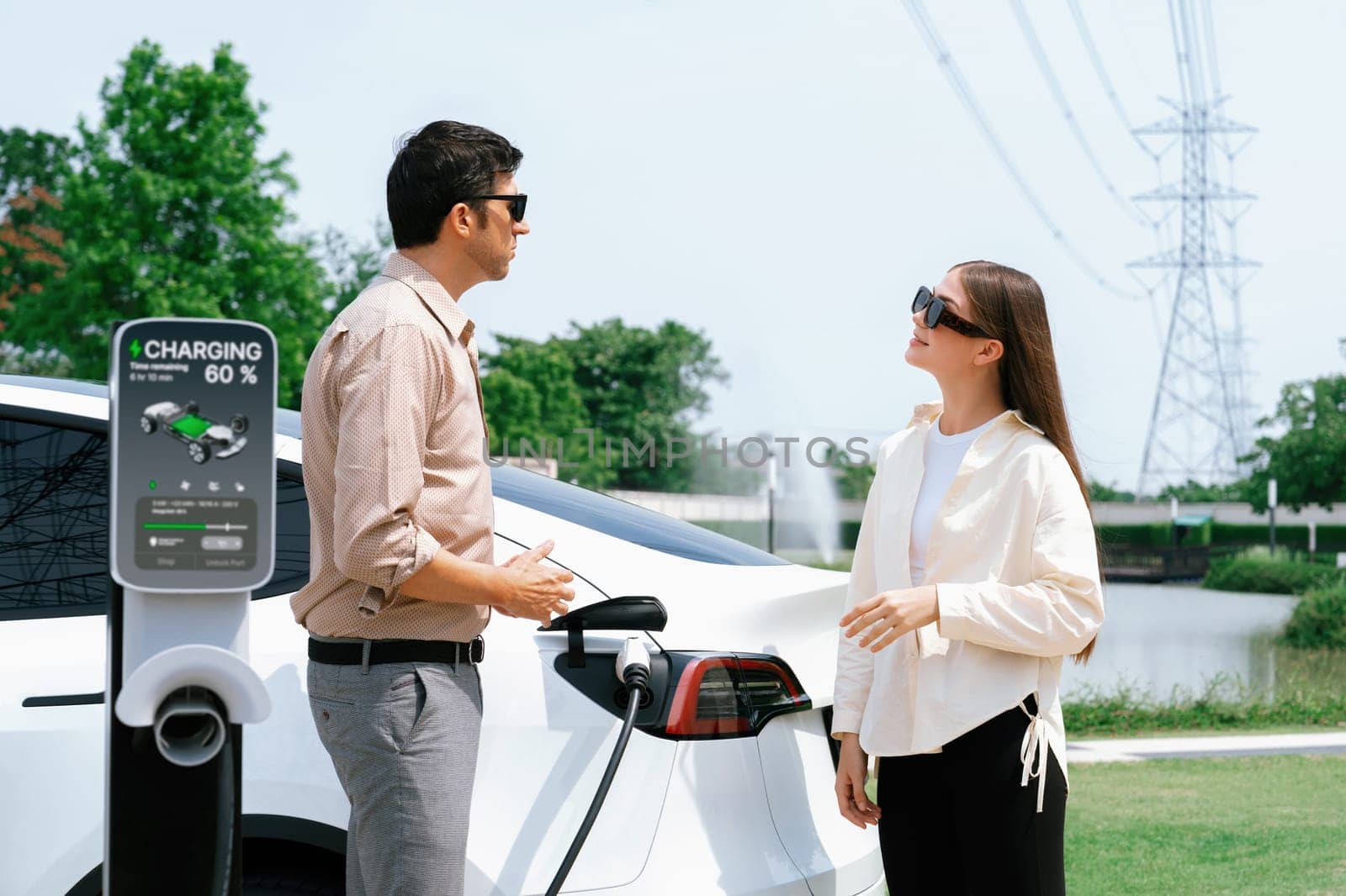 Young couple recharge EV car battery at charging station. Expedient by biancoblue