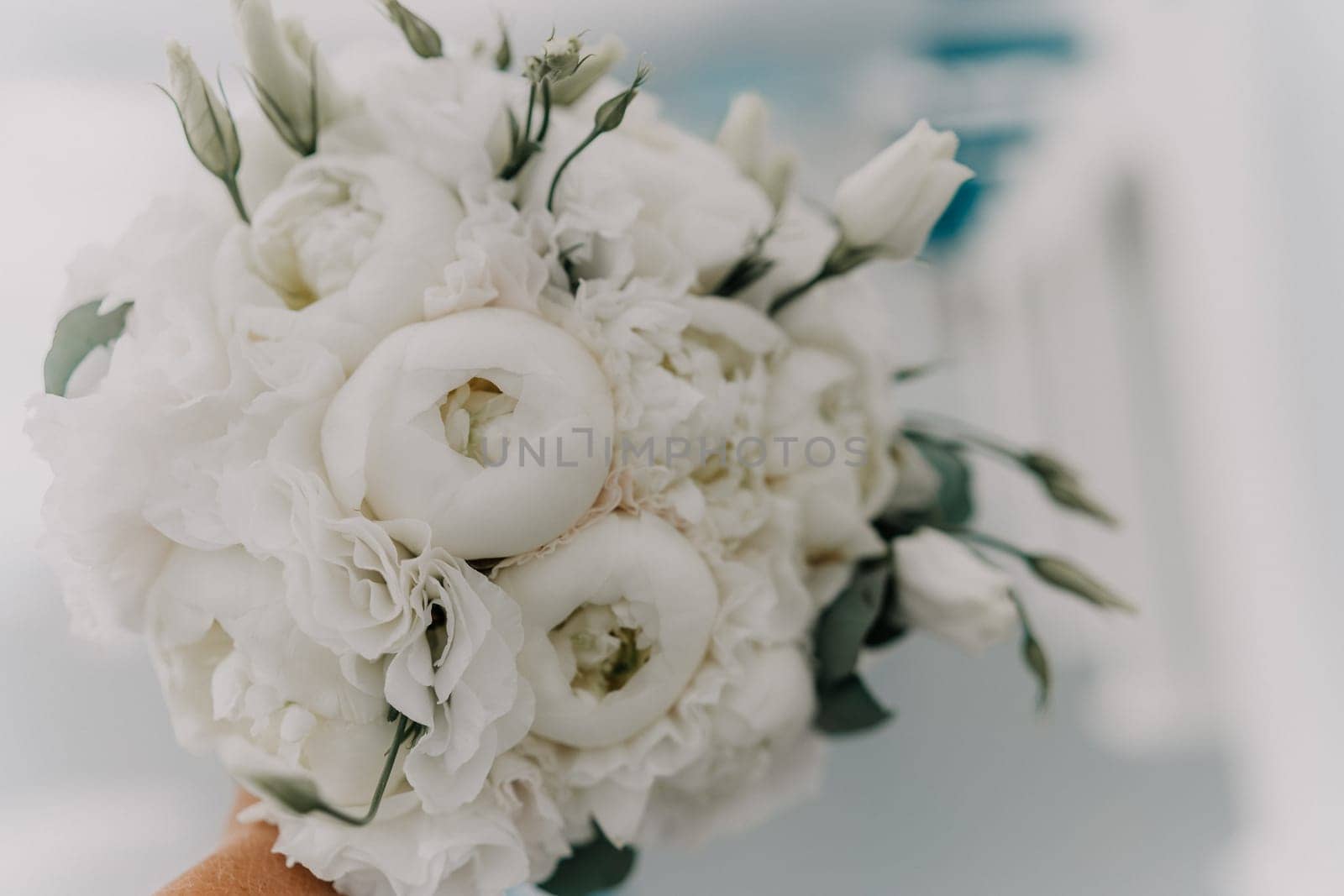 A bouquet of white flowers is being held by a person. The flowers are arranged in a way that they are not too close to each other, giving the impression of a beautiful and elegant arrangement