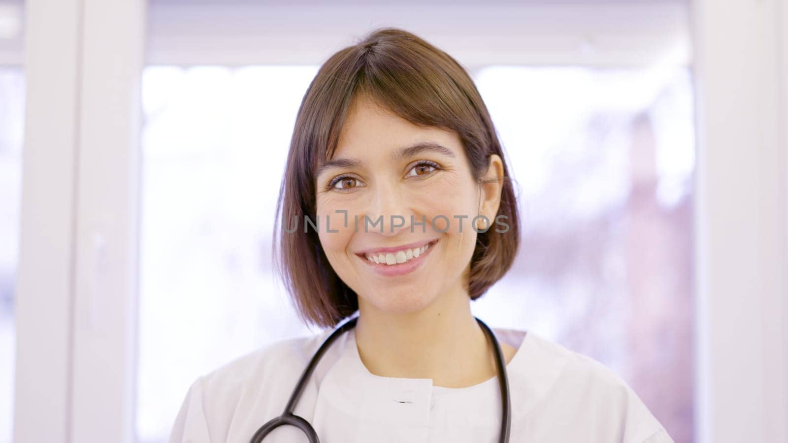 Female doctor smiling at camera in the clinic by ivanmoreno