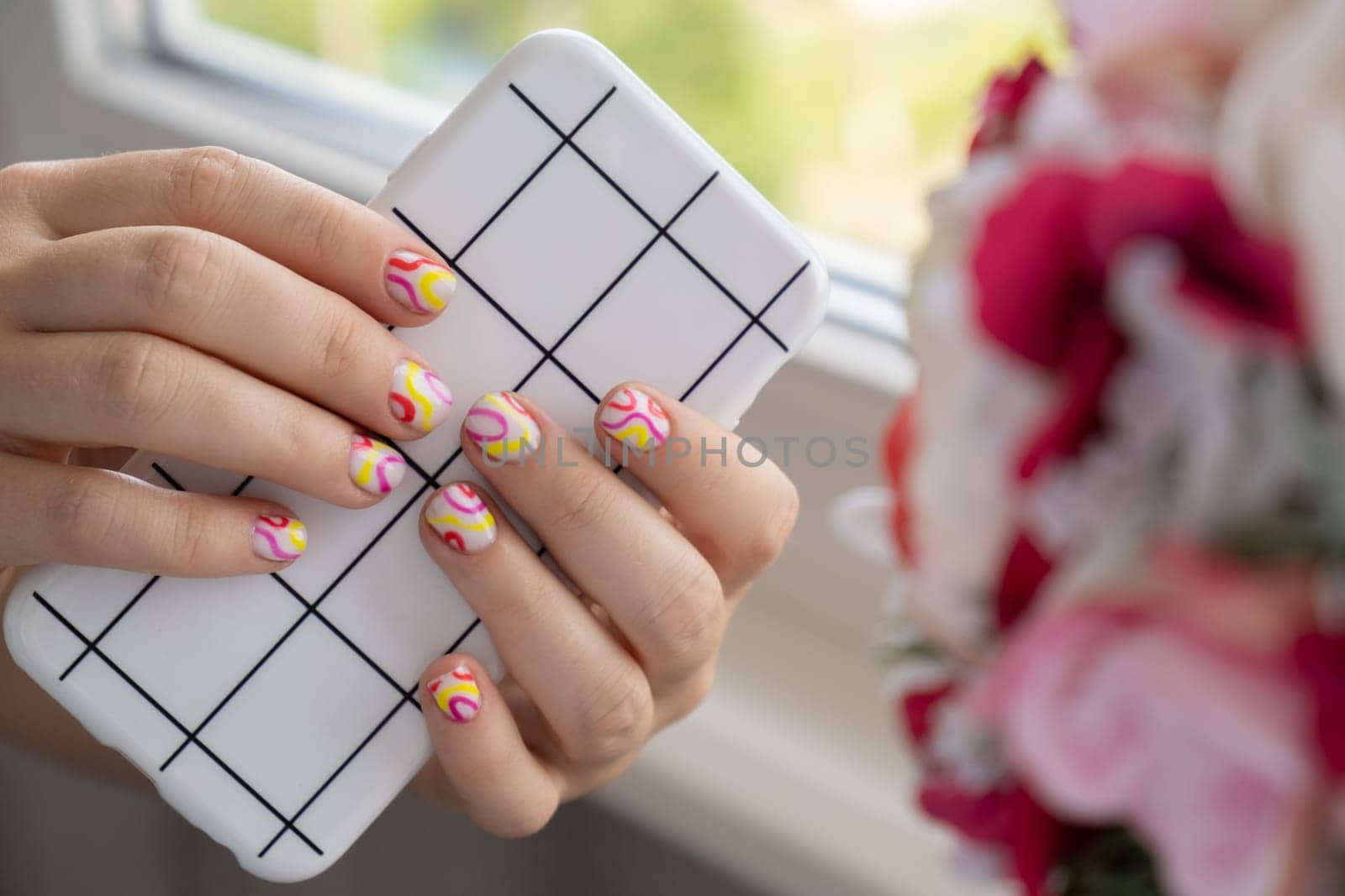 Stylish summer colorful nails female manicured hands holding mobile phone. Closeup of manicured nails of woman hand. Summer style of nail design concept. Beauty treatment.