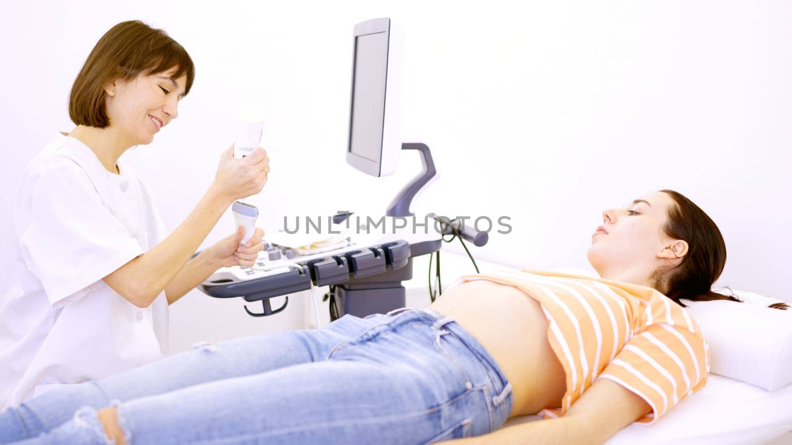 Female doctor getting ready to perform an ultrasound to a pregnant woman