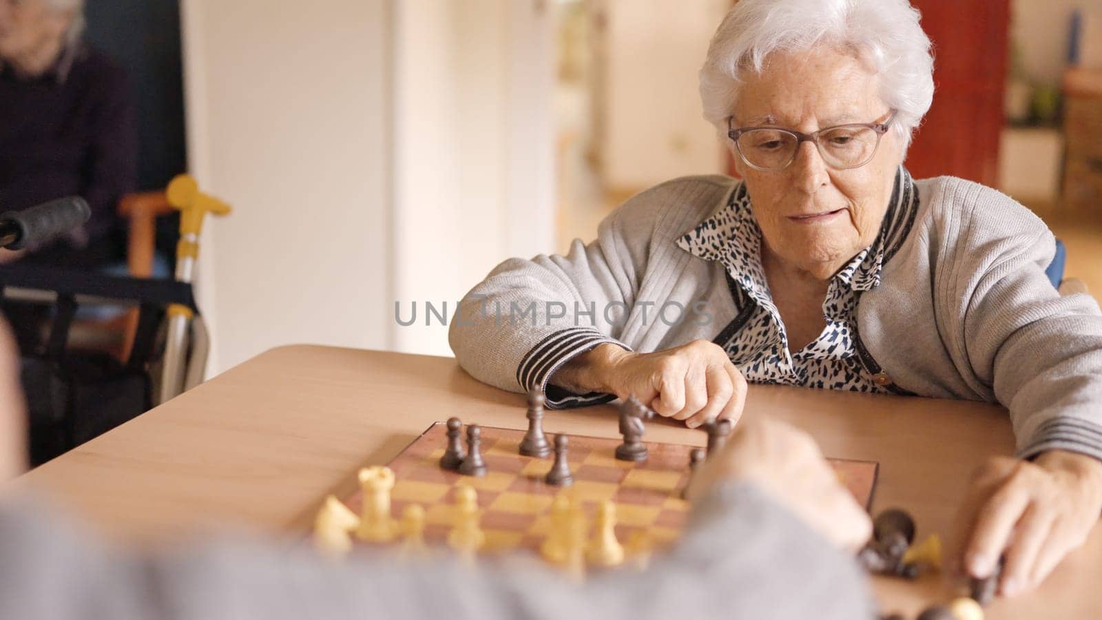 Two female senior friends playing chess in a nursing home