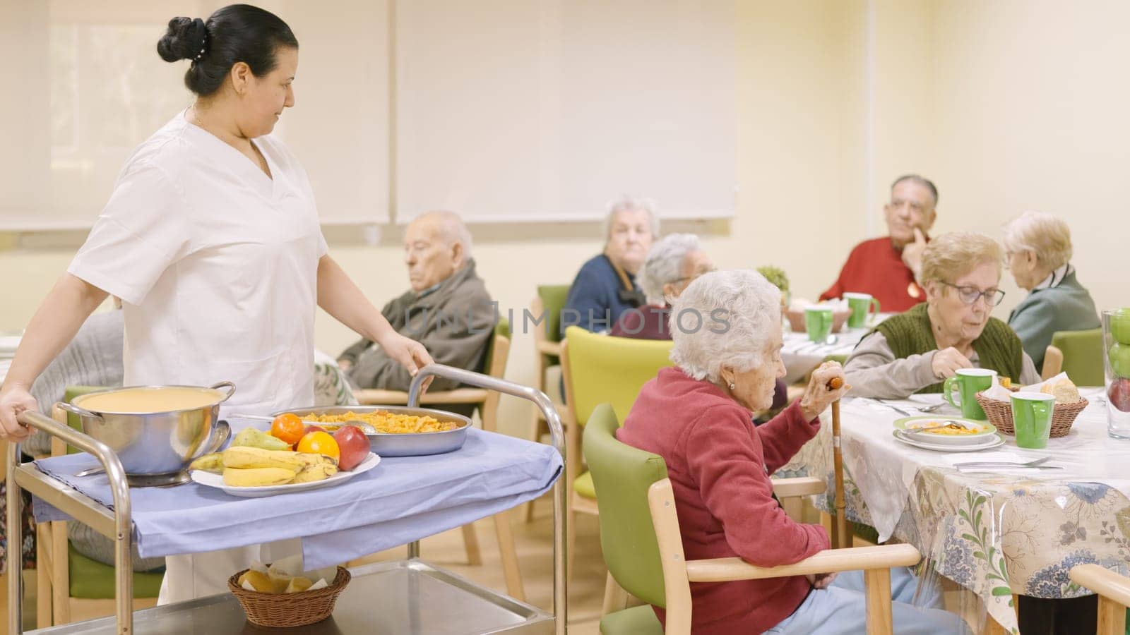 Female cook entering with food to the dining room of geriatric