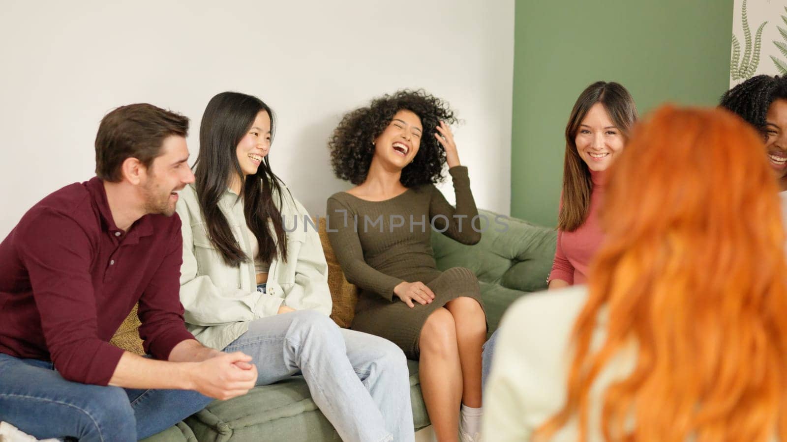 Multi-ethnic diverse group of people laughing sitting on the sofa