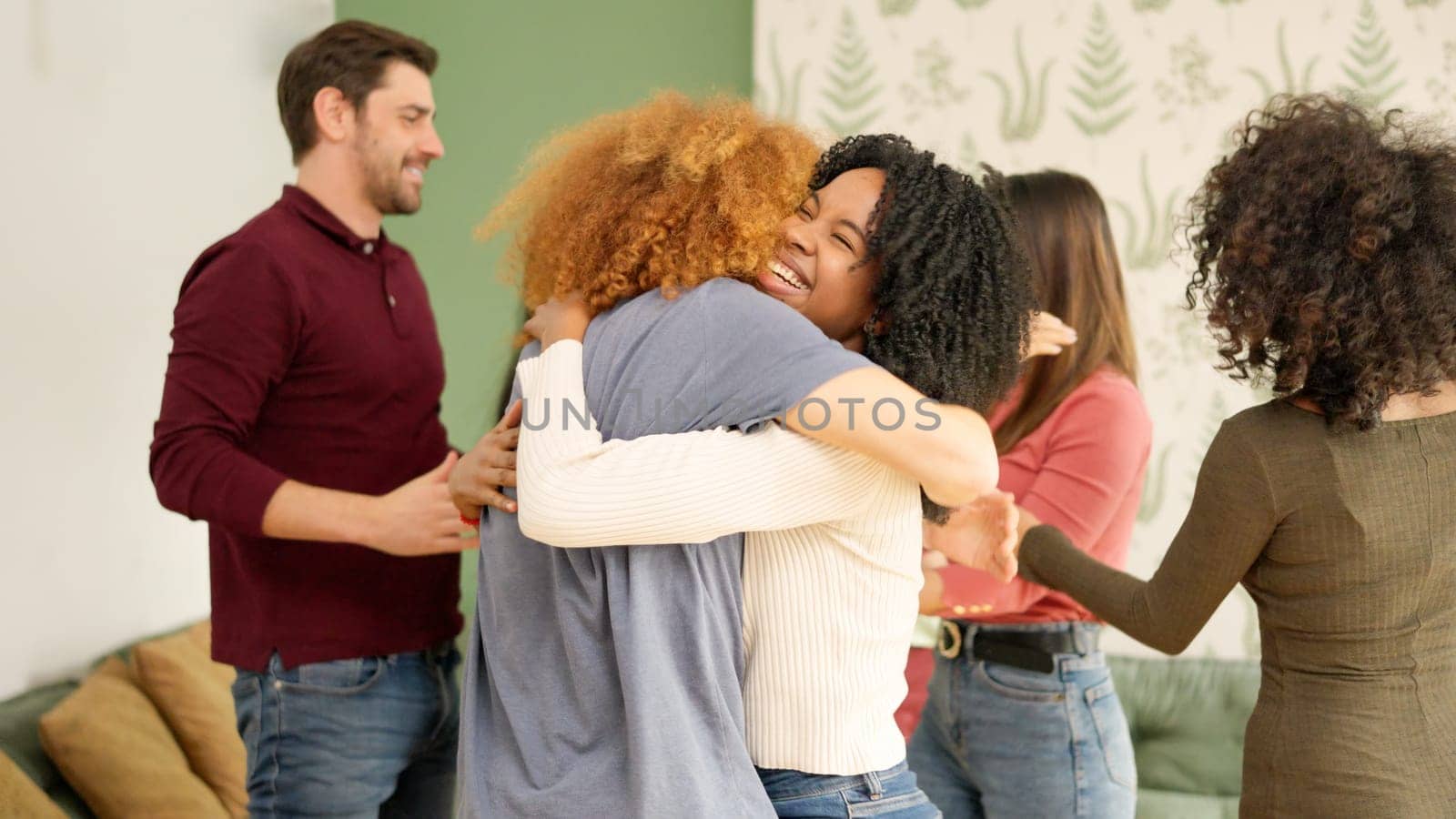 Happy meeting of diverse friends embracing together at home