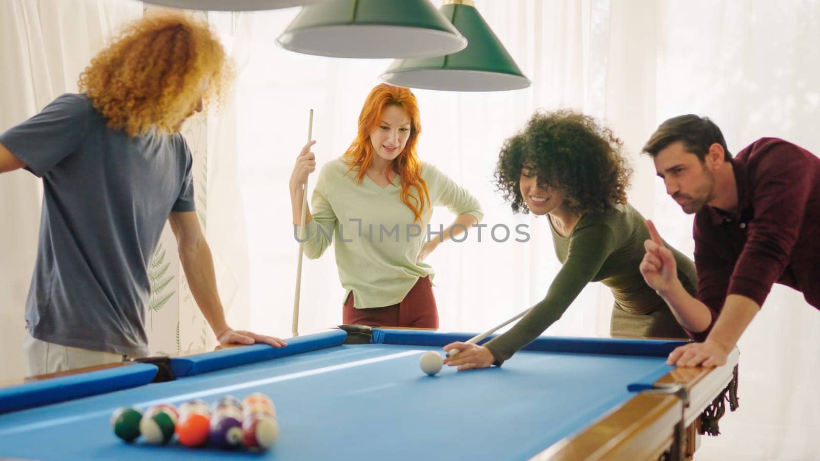 A beginner player hitting a billiard ball and laughing happy next to friends