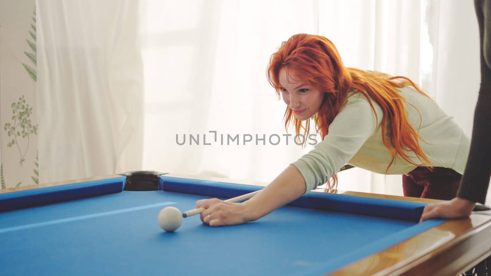 Concentrated woman hitting a pool ball playing with friends at home