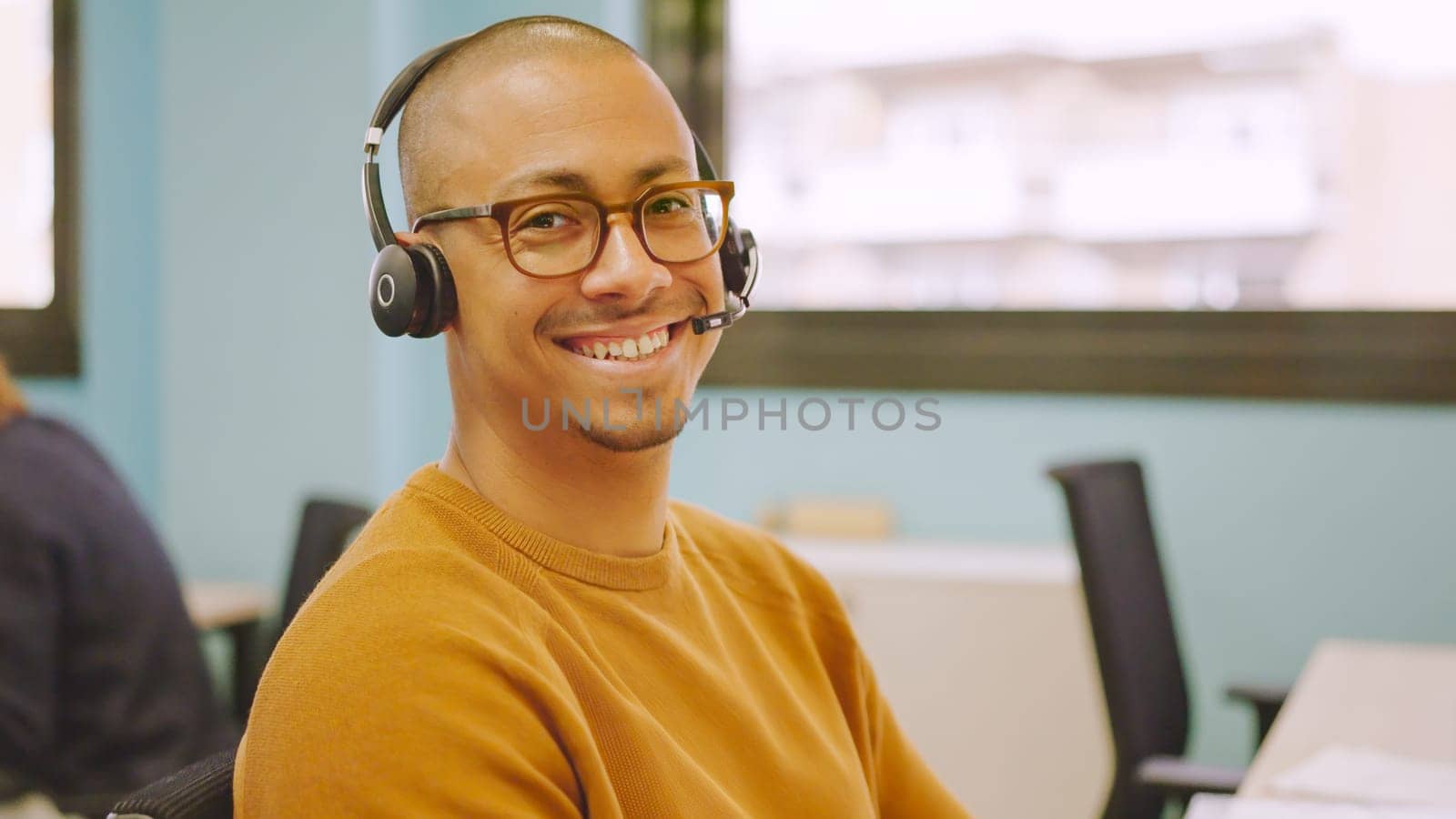 Smiling man using headset while working in a coworking by ivanmoreno