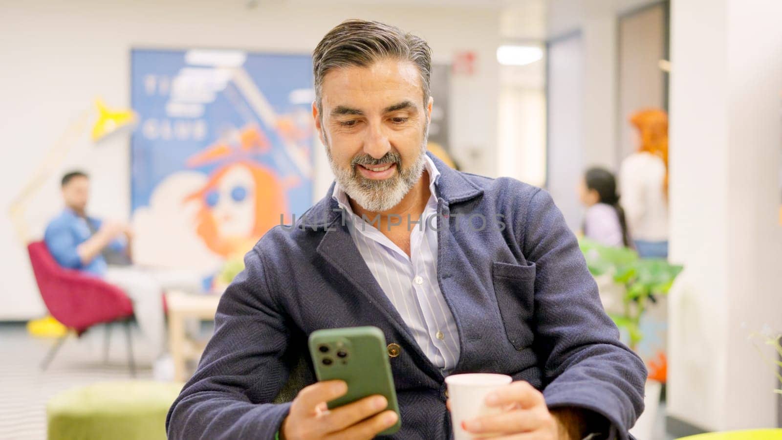 Mature employee using phone in modern coworking by ivanmoreno