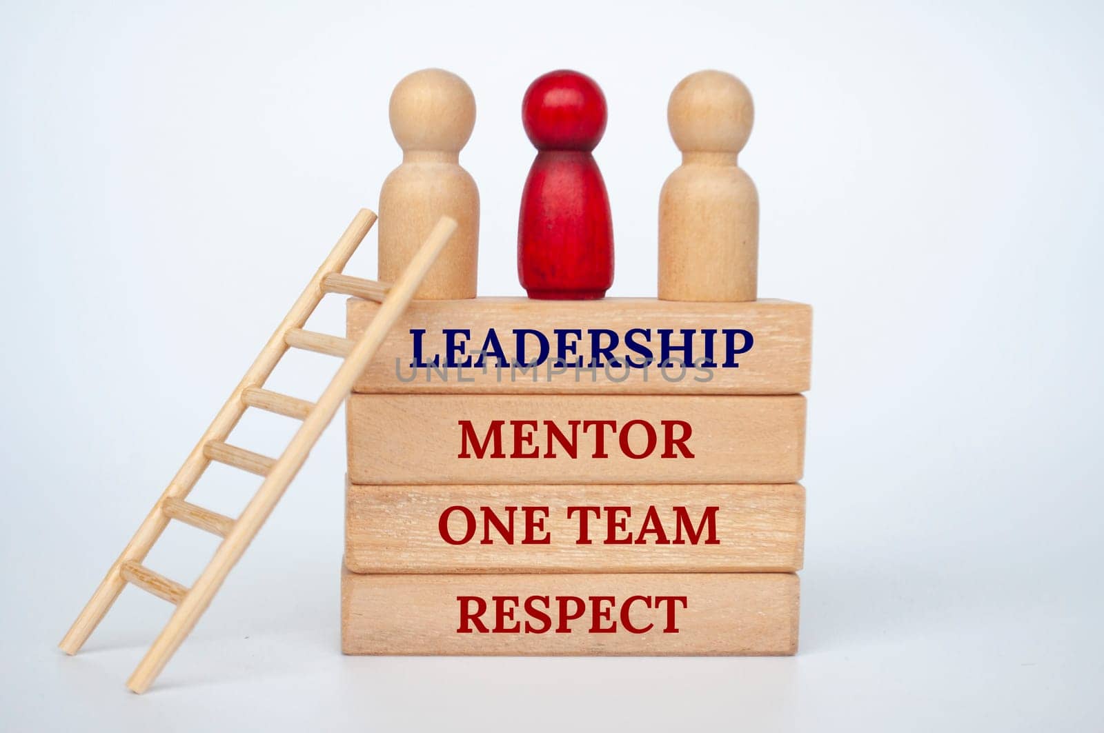 Leadership concept with doll figures on top of wooden blocks with wooden ladder.