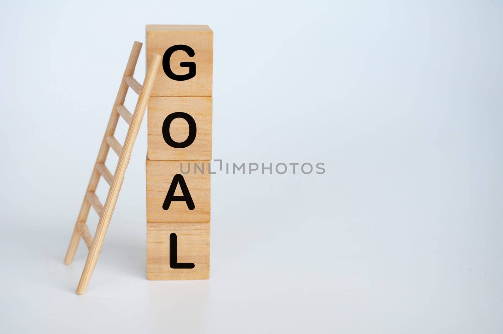 Goal text on wooden cubes with ladder on white background.