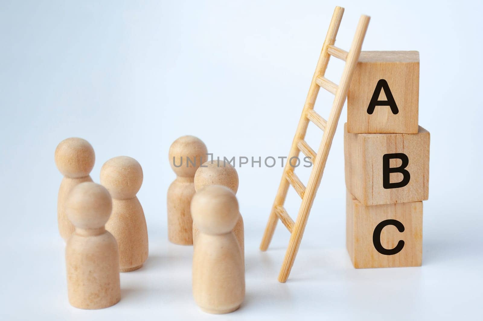 ABC text on wooden cubes with ladder and doll figures on white background. Knowledge concept.