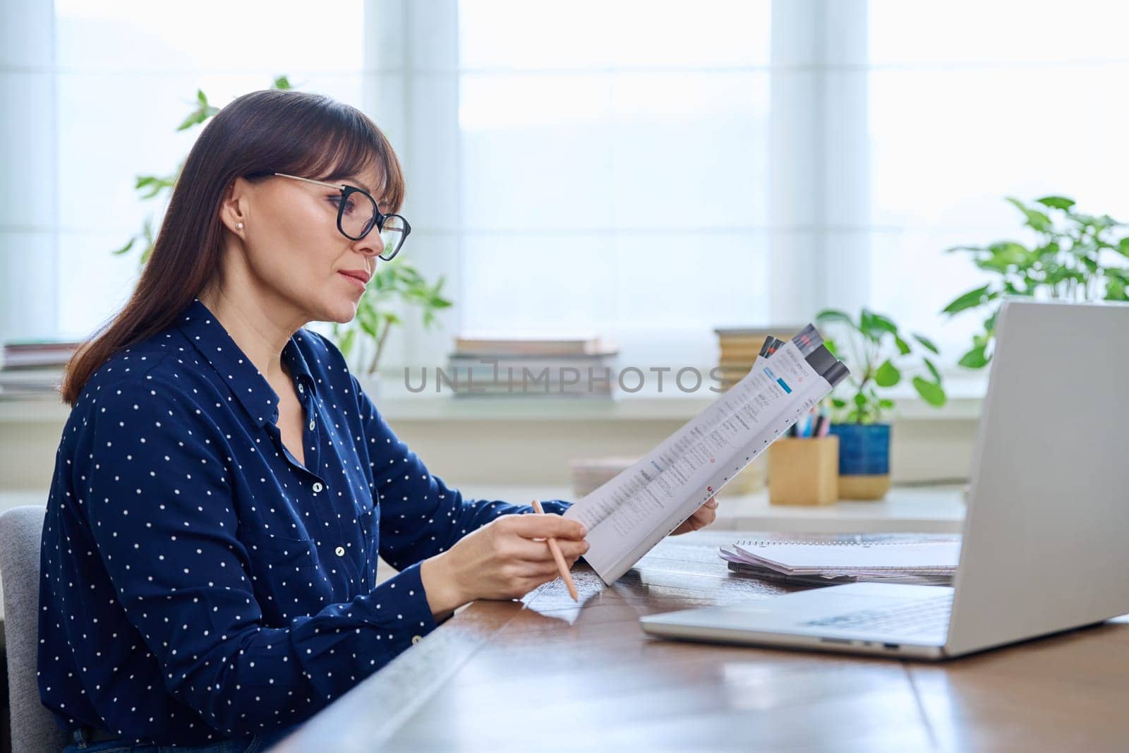 Woman teacher with textbook working online using computer by VH-studio