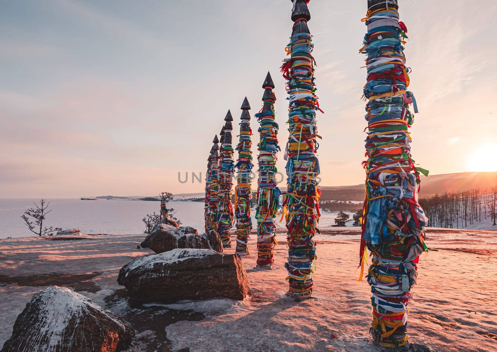 Traditional buryat shaman sacred pillars with colorful ribbons in winter at sunset, cape Burkhan, Olkhon island. Winter Baikal. by Busker