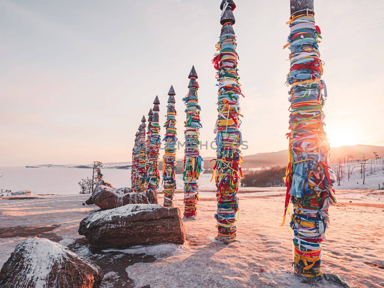 Traditional buryat shaman sacred pillars with colorful ribbons in winter at sunset, cape Burkhan, Olkhon island. Winter Baikal. by Busker