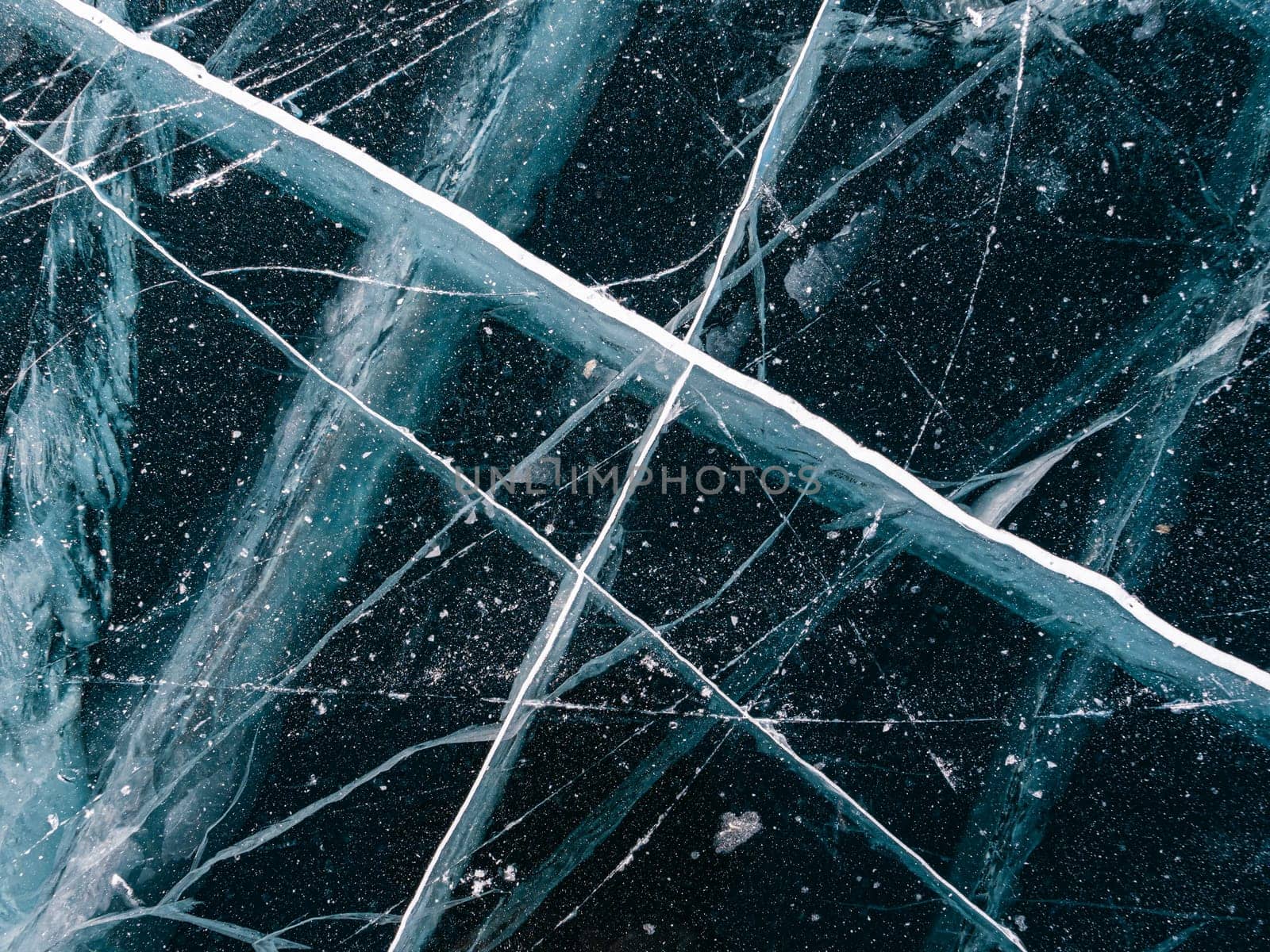 Aerial top down view on the blue cracked ice of the lake Baikal. Winter landscape, frozen lake. Ice kingdom.