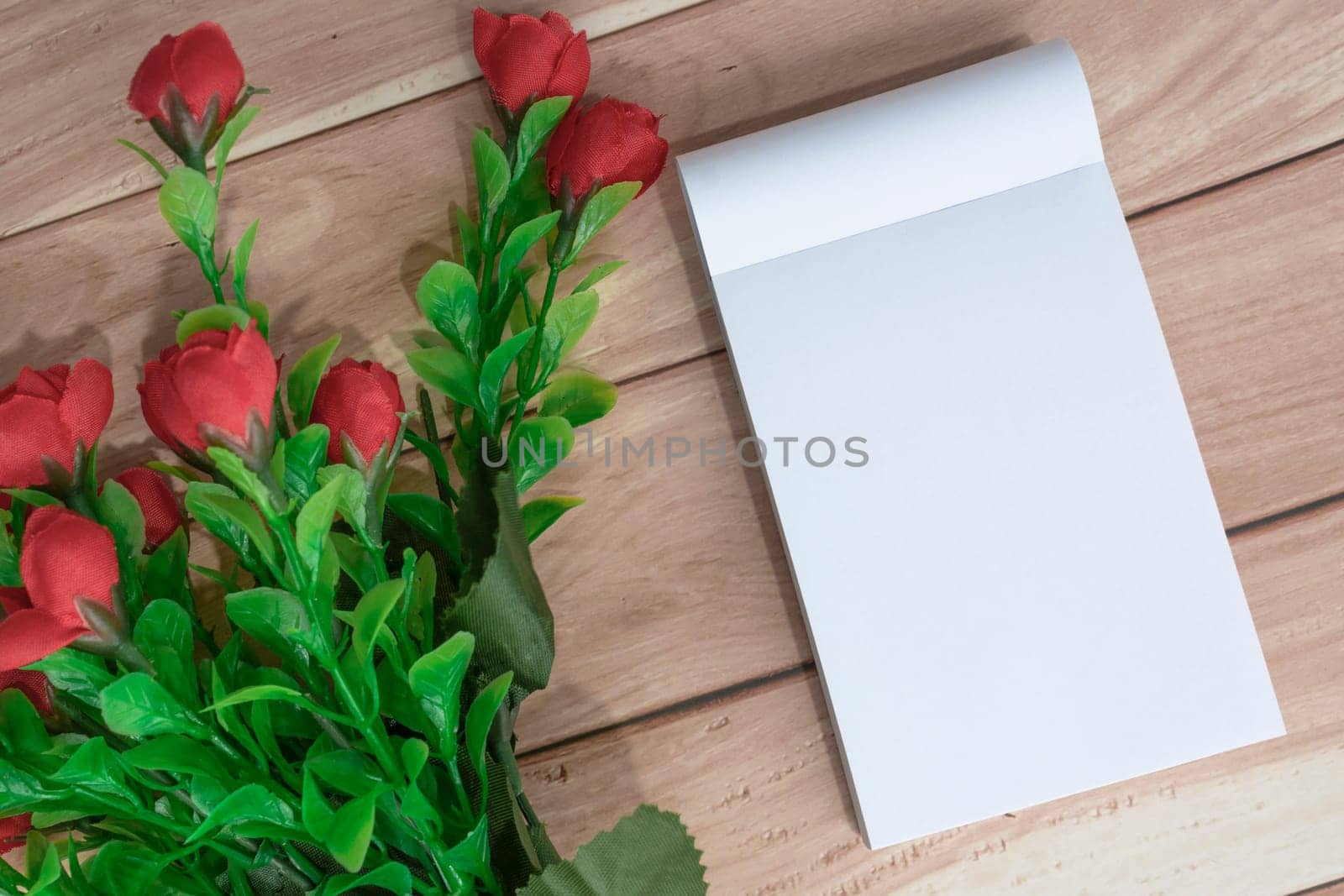 Note book with flowers on wooden desk. Directly above. Flat lay. Copy space.