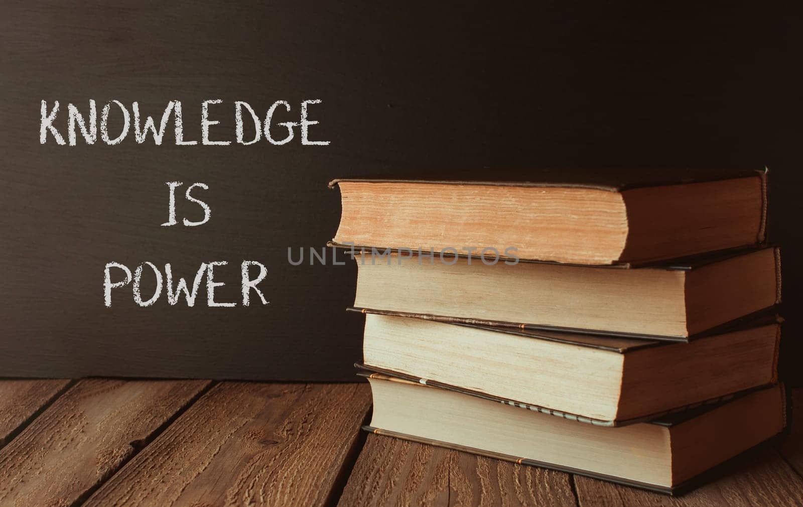 Knowledge is power. The books stacked on top of each other symbolize the importance of education and learning. The chalkboard behind the books serves as a reminder to always seek knowledge