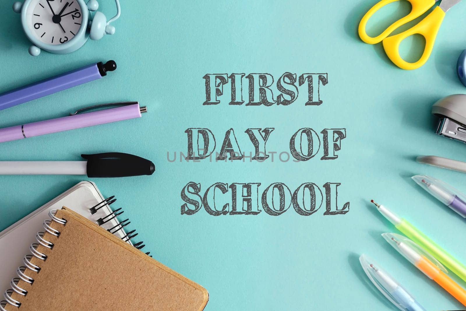 A blue background with a clock, scissors, pens, and pencils. The words first day of school are written in white