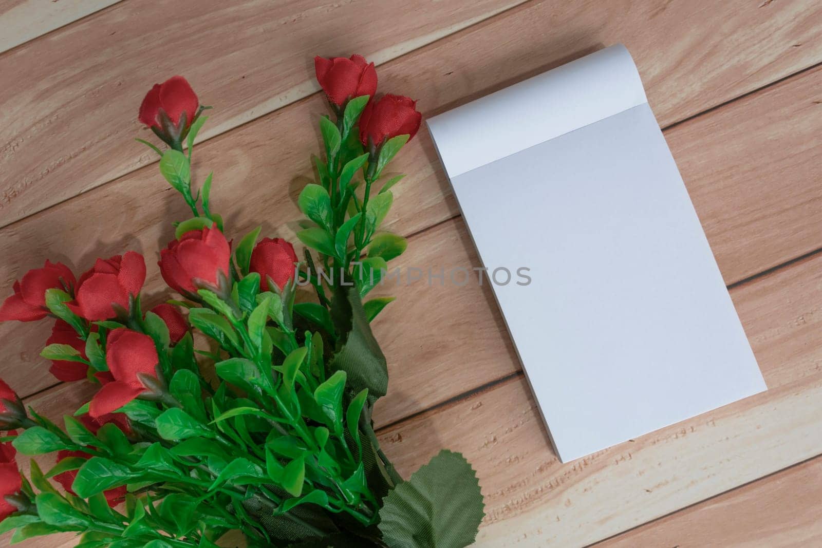 Note book with flowers on wooden desk. Directly above. Flat lay. Copy space.