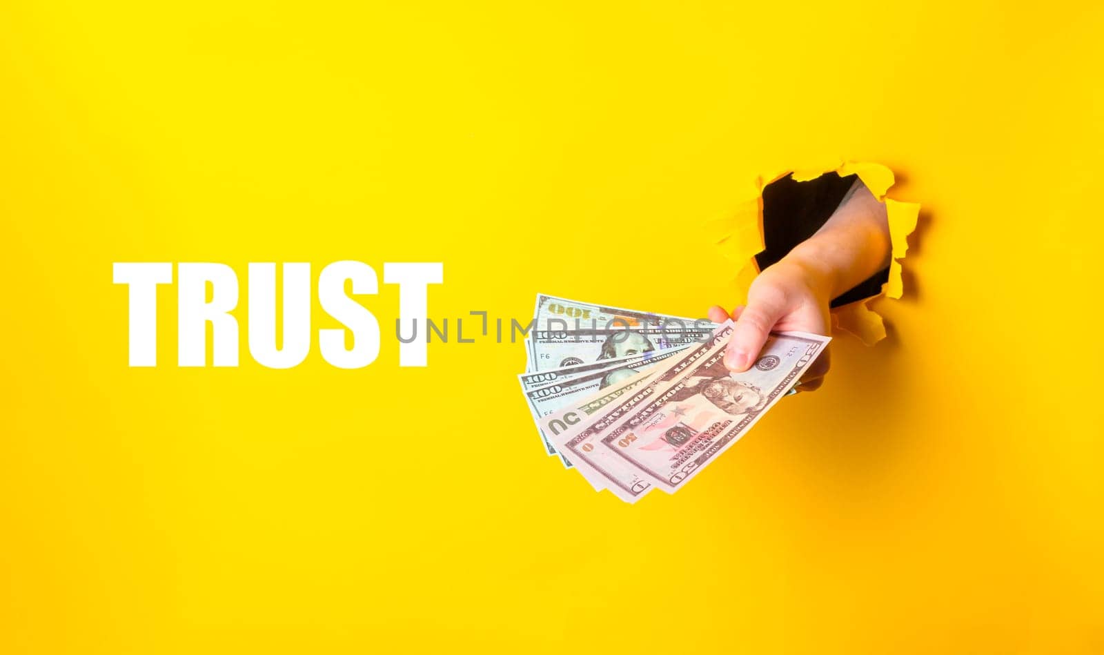 A hand holding a stack of money with the word trust written below it. Concept of financial security and the importance of trust in financial transactions