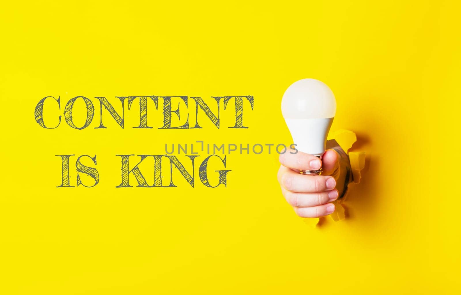 A person holding a light bulb with the words content is king written behind them. The image conveys the idea that content is king, emphasizing the importance of creating valuable and engaging content