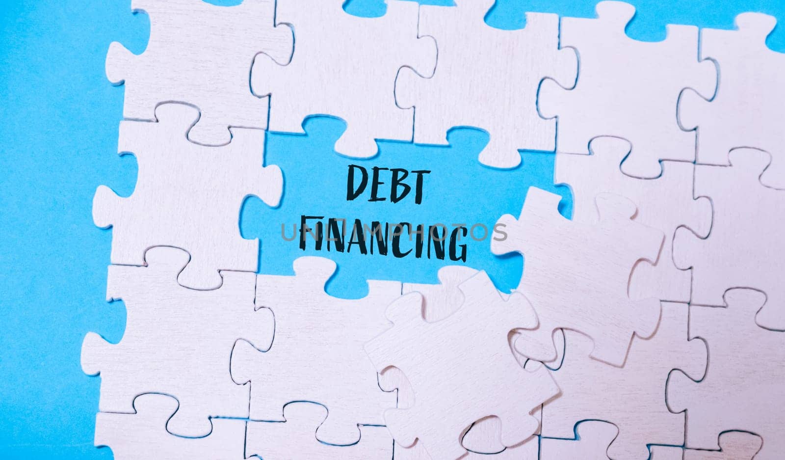 A jigsaw puzzle featuring the words debt financing in the center, illustrating the complexity and strategic nature of financial arrangements.