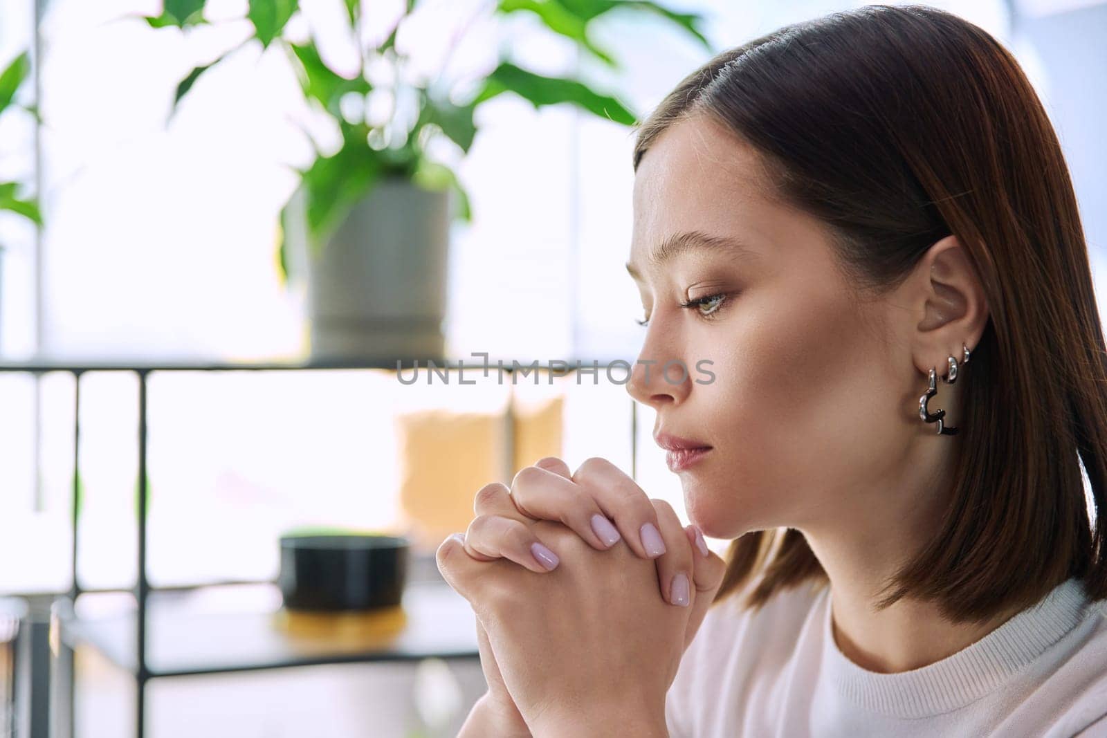 Excited sad upset serious young woman with folded hands, face in profile close-up. Emotions stress depression troubles difficulties, mental health, youth lifestyle concept