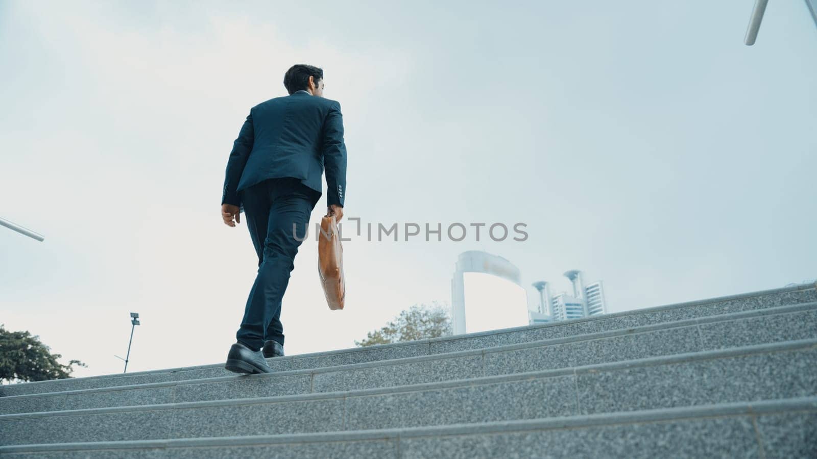 Top view of smart business man walking up stairs with bag in the hand. Professional project manager climb up the stair and going to workplace. Increasing skill, getting promotion, traveling. Exultant.