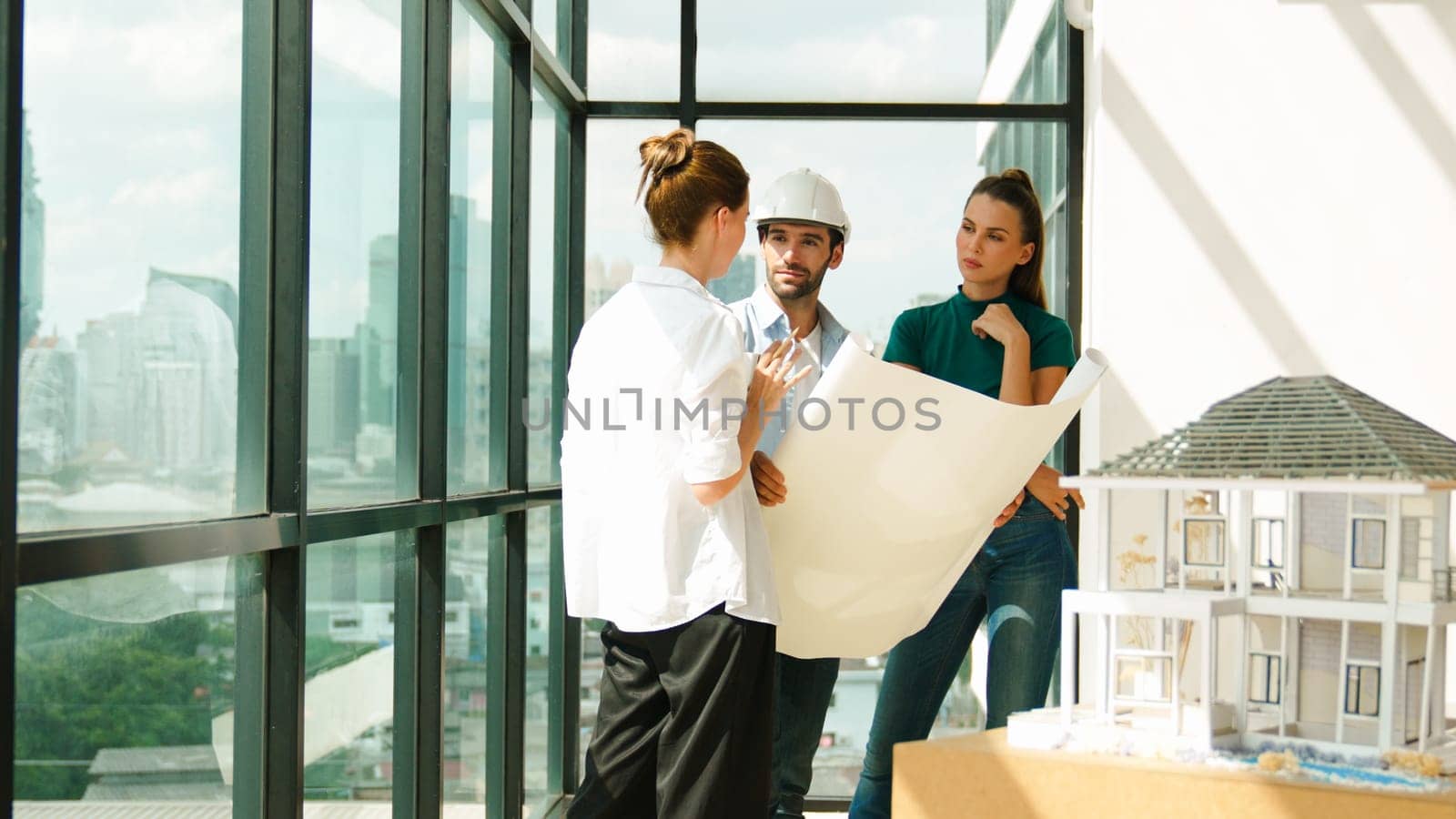 Professional architect engineer team talking, sharing, brainstorming about design while manager hold at project plan. Young architect holding plan while manager listen and point at plan. Tracery