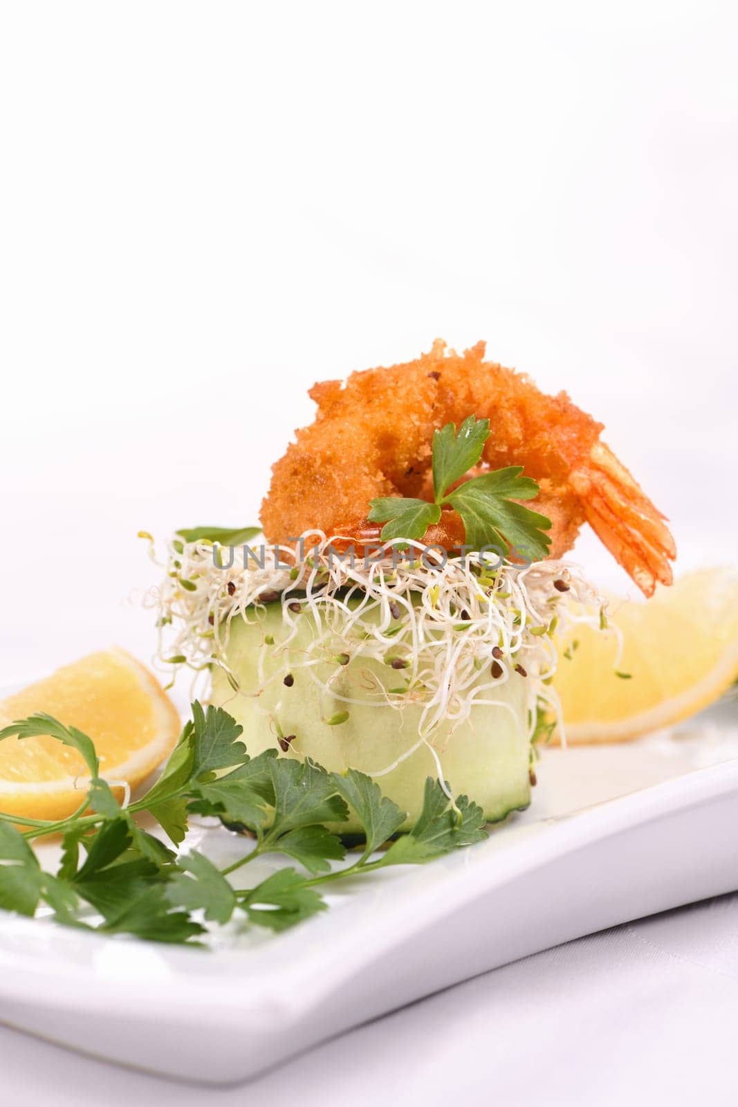 Cucumber appetizer with fried breaded shrimp on a bed of microgreens