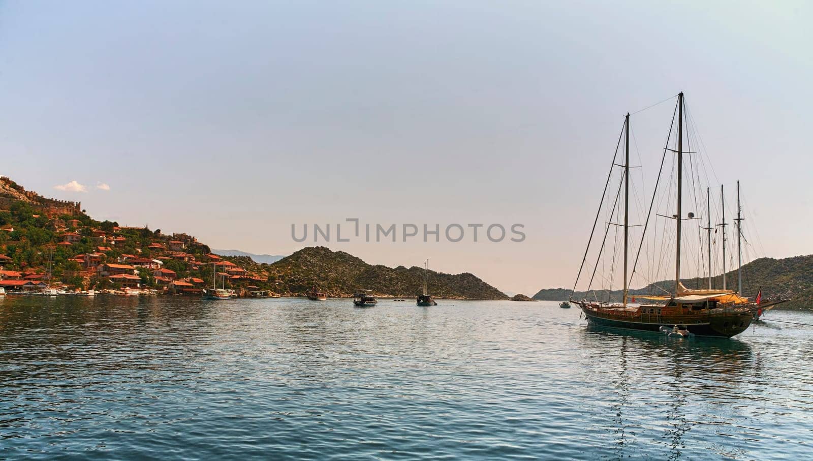 Yachts docked in a beautiful bay with lush green mountains in the background by Hil