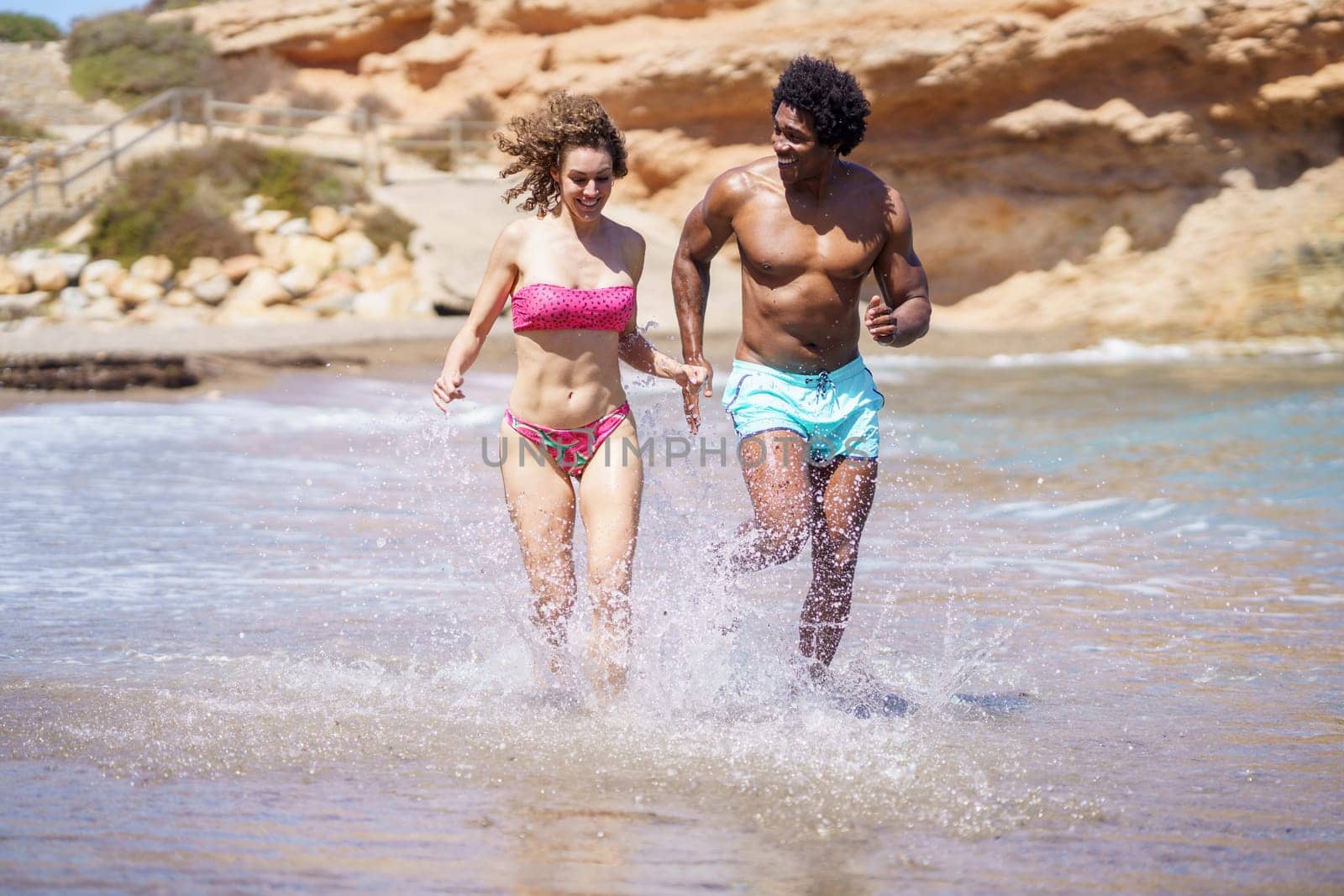 Happy diverse couple jogging in sea water by javiindy