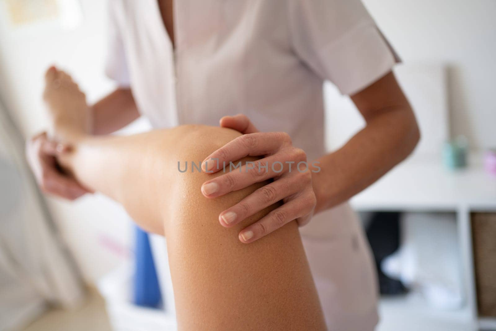 Professional physiotherapist treating knee of patient by javiindy