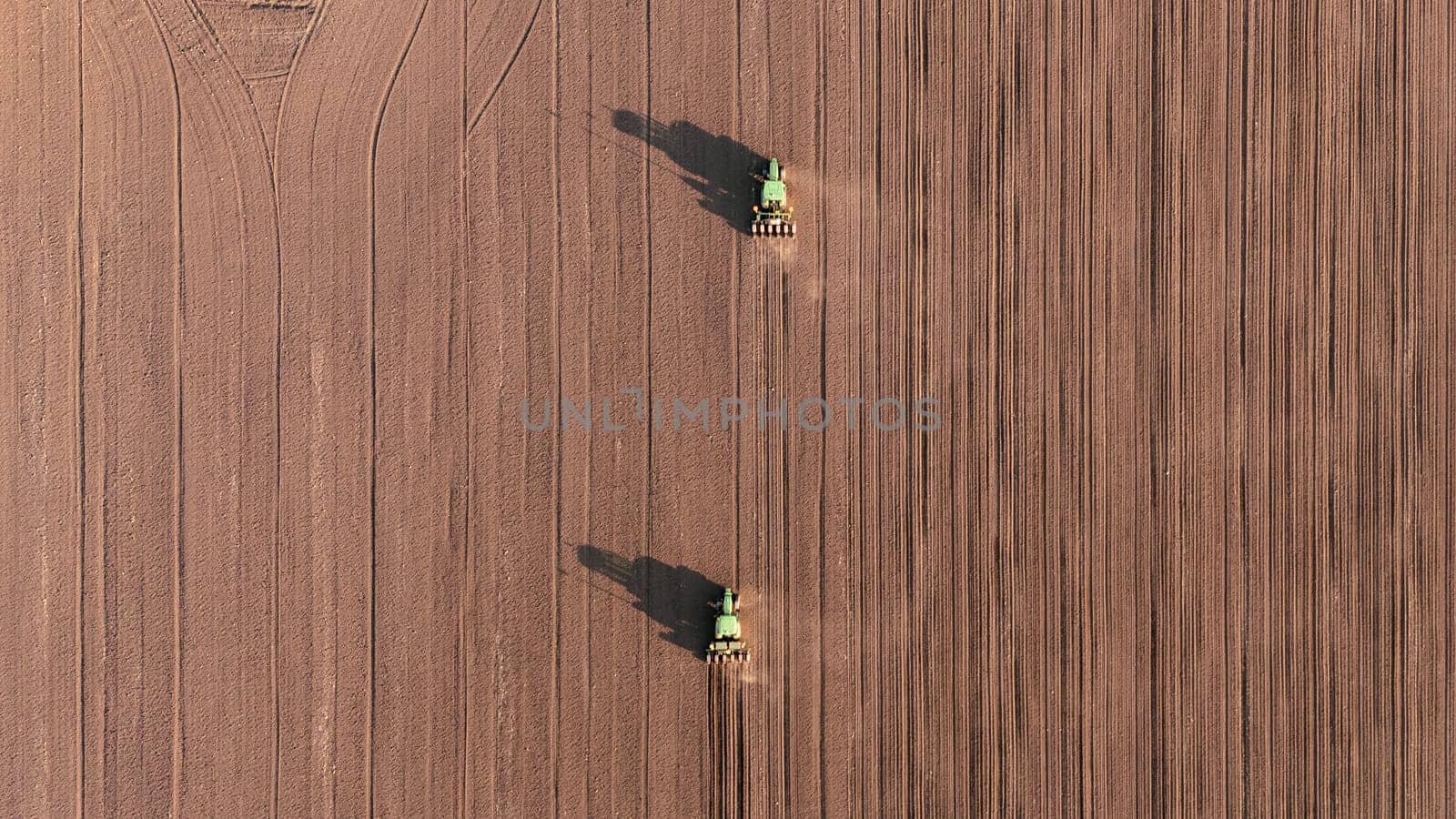 Seeds to sow. Few Tractors with seed drills sowing the crop, top down view from drone