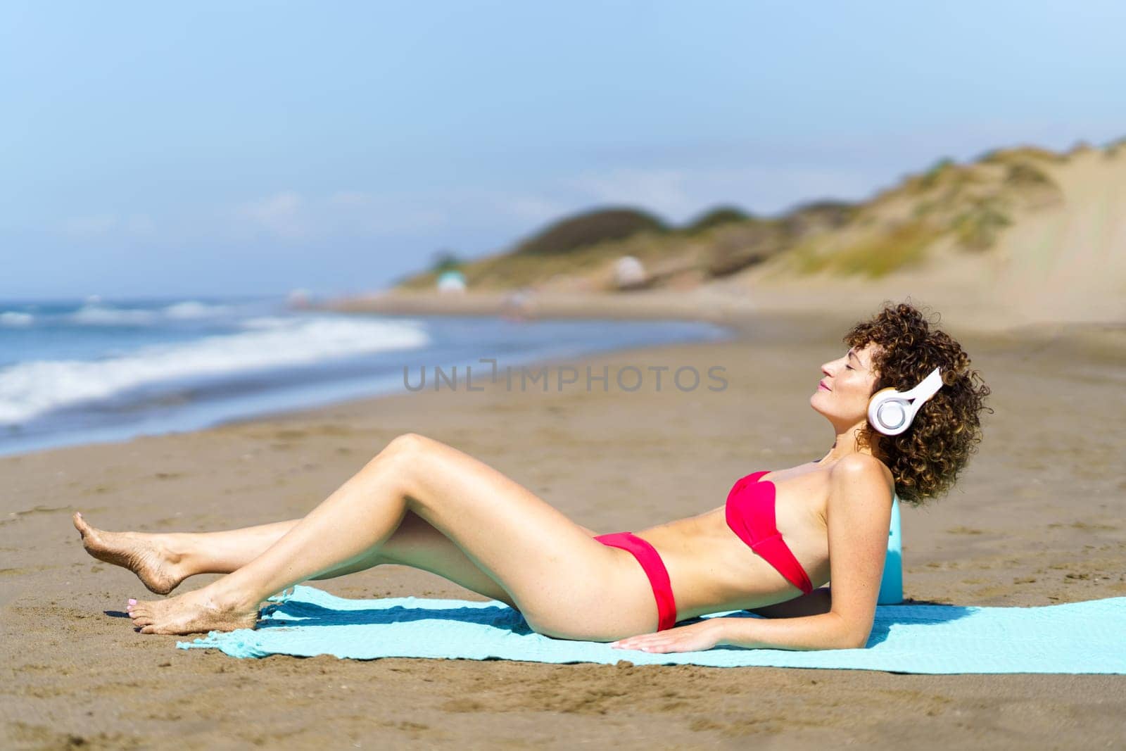 Content woman in headphones chilling on beach by javiindy